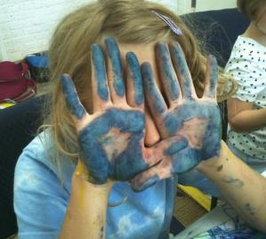 child with her hand covered in paint